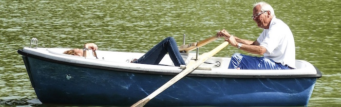 An old man and a woman in a row boat on a lake