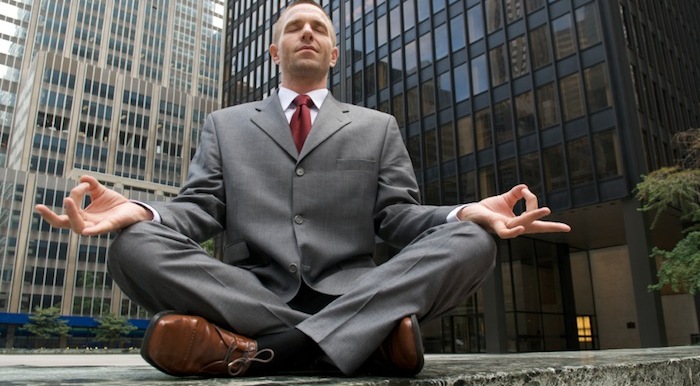 Man doing yoga in a suit in the middle of the city