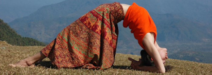 Woman doing a yoga backbend pose on a mountain