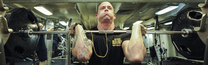 Tattooed man lifting weights in a gym
