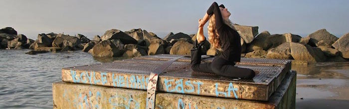 Woman doing yoga on a platform at the ocean