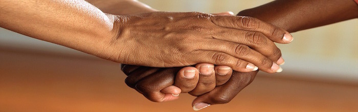 Close-up shot of two people clasping hands