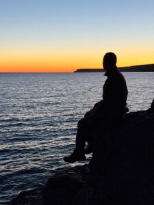 author sitting by the water just before sunrise, which is an effective somatic practice